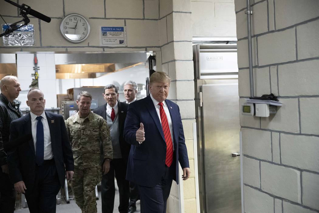 President Donald Trump gives thumbs up as he walks to serve dinner during a surprise Thanksgivi ...