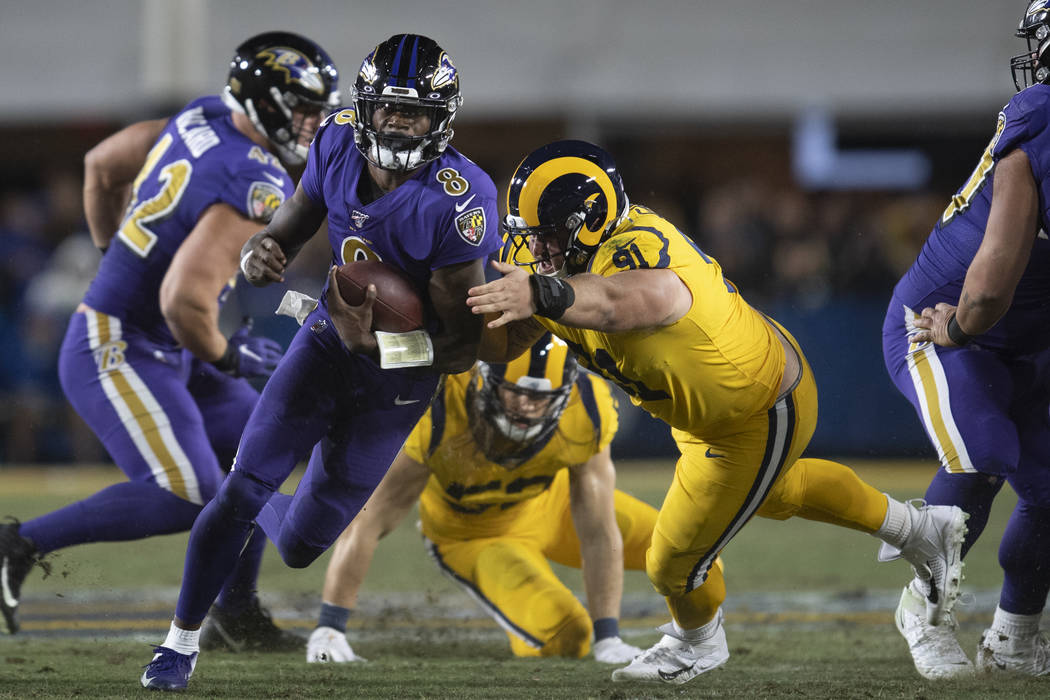 Baltimore Ravens quarterback Lamar Jackson, second from left, sprints with the ball past Los An ...