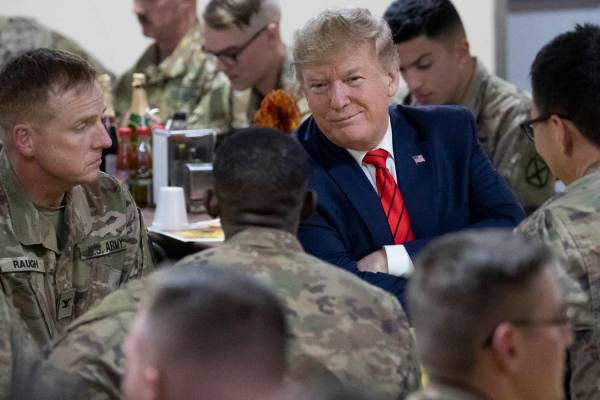 President Donald Trump smiles while sitting with the troops during a surprise Thanksgiving Day ...