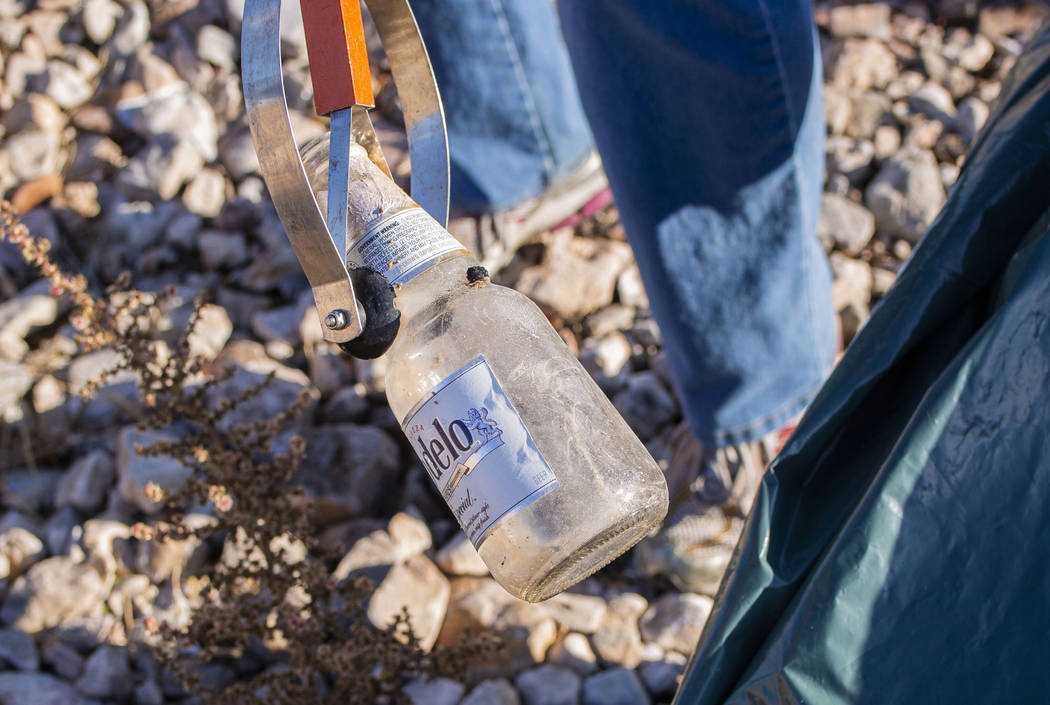A volunteer for Get Outdoors Nevada picks up a glass beer bottle near the trail leading to the ...