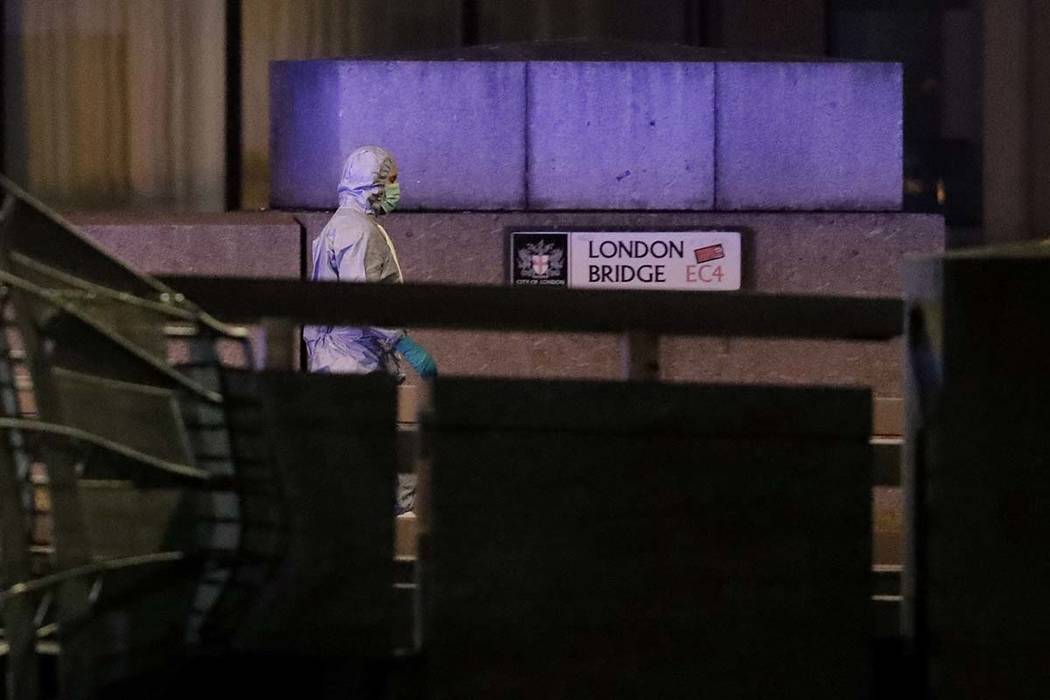 A police forensic officer walks by a sign where a man was shot dead by police on London Bridge ...