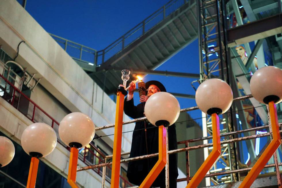 Rabbi Shea Harlig lights the shamesh candle that's used to light the other candles on the Grand ...