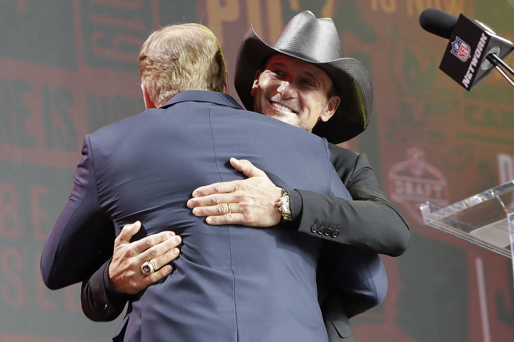 Country music star Tim McGraw hugs NFL Commissioner Roger Goodell ahead of the second round of ...