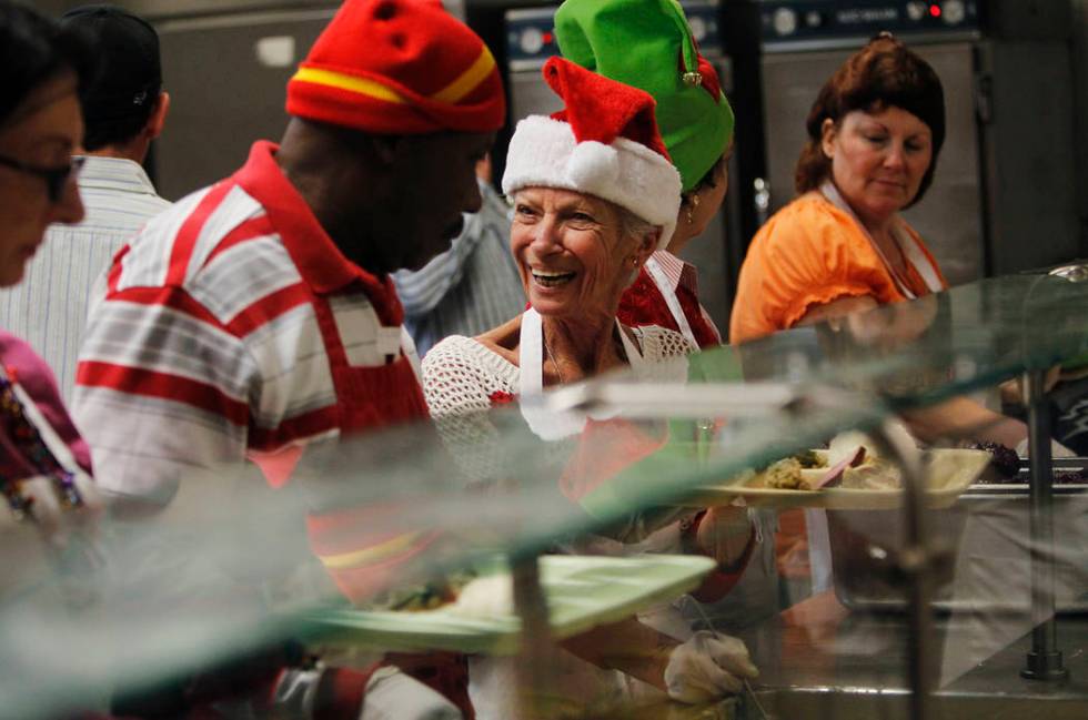 Volunteers Barbara Pickett, middle, and Henry Brown interact while preparing holiday meals duri ...