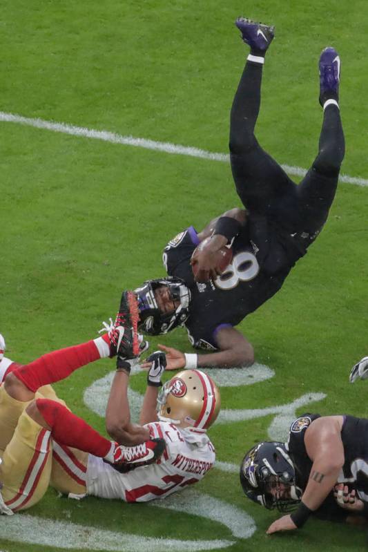 Baltimore Ravens quarterback Lamar Jackson (8) flips over after being tripped by San Francisco ...