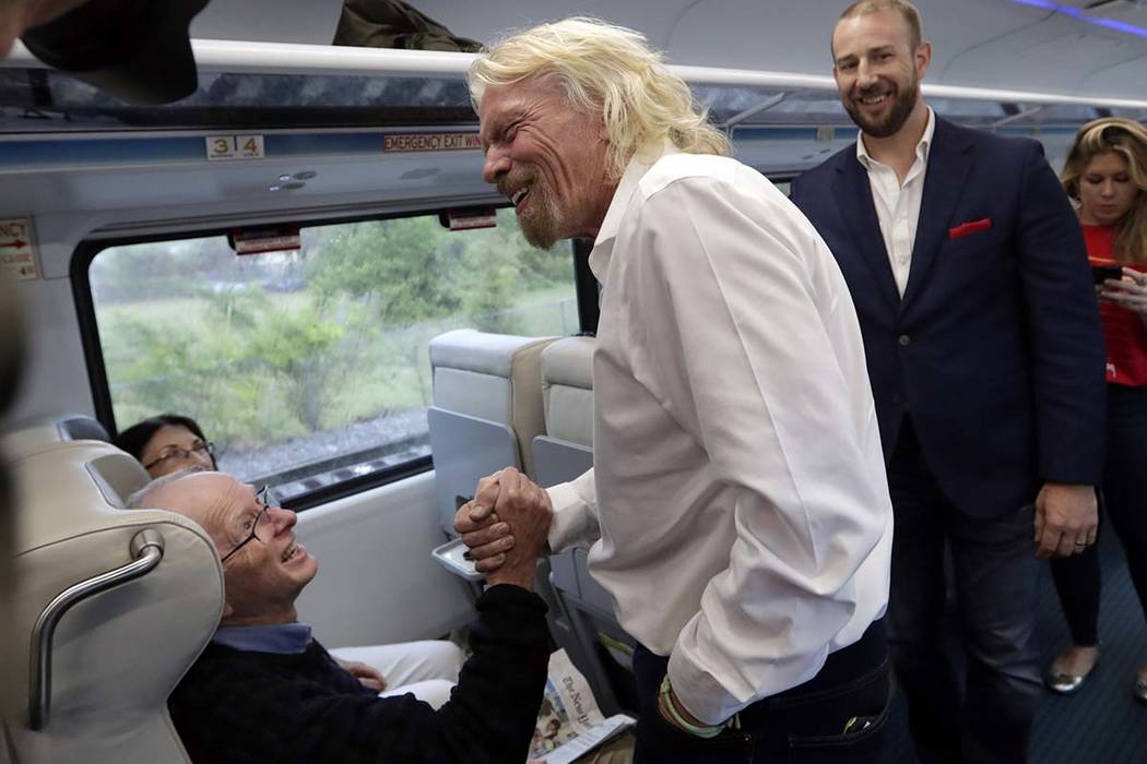 Richard Branson, of Virgin Group, center, greets a passenger while riding a Brightline train fr ...