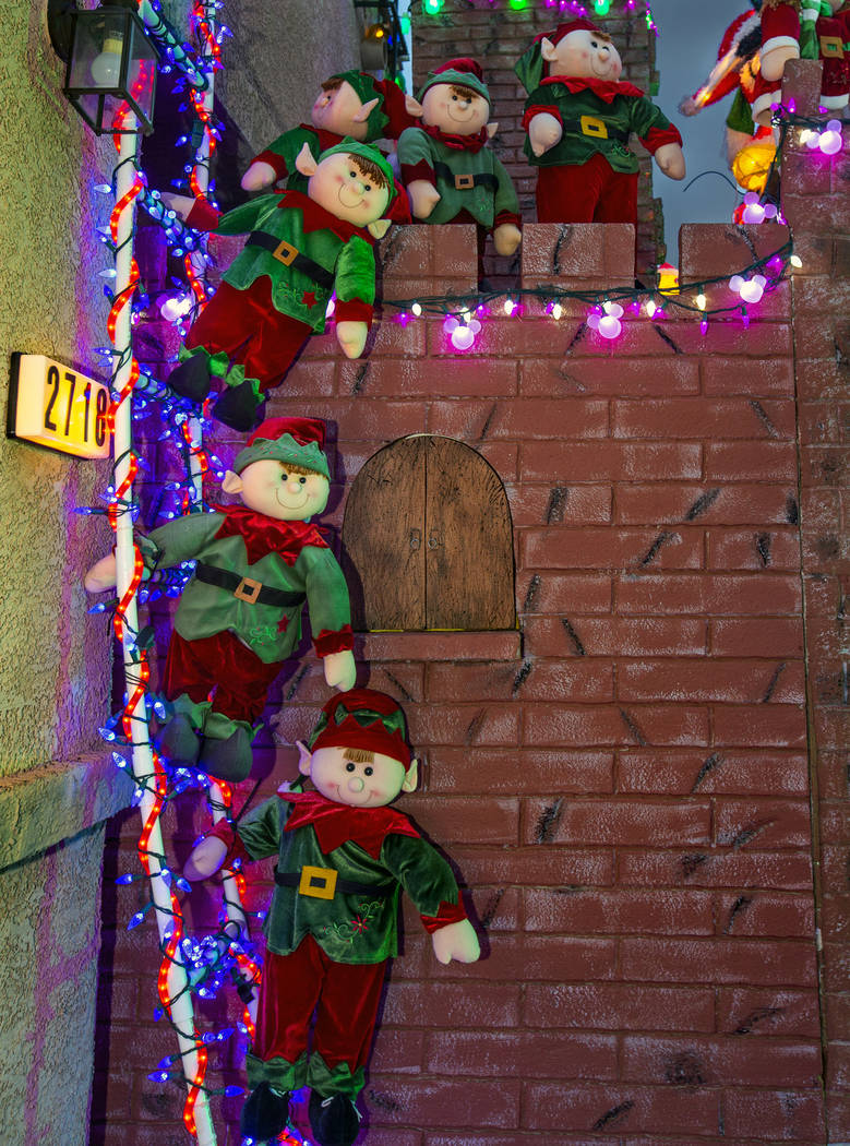 A group of elves on a ladder as part of the holiday lights display in the yard of Maria and Jua ...