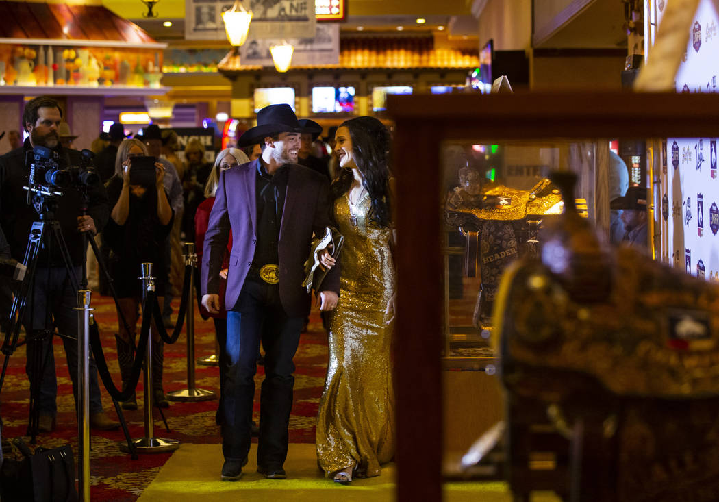 National Finals Rodeo contestant Caleb Bennett walks with his wife, Savannah, on the gold carpe ...