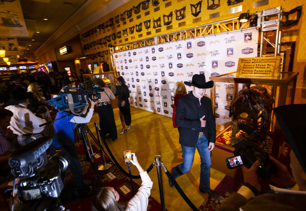 National Finals Rodeo contestant Kaycee Feild, of Spanish Fork, Utah, walks on the gold carpet, ...