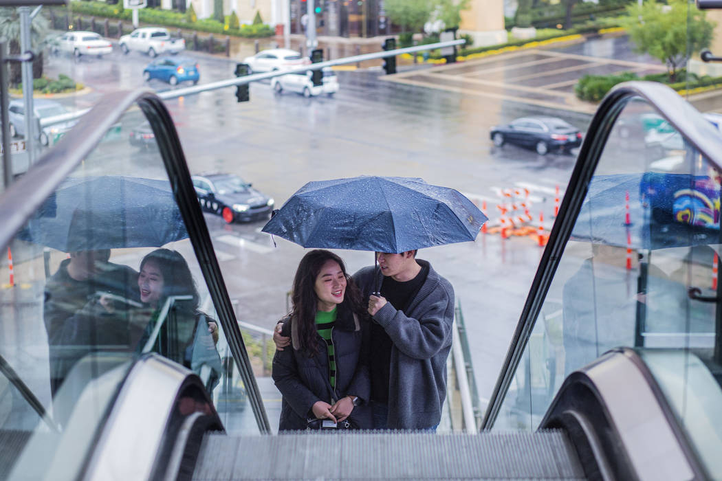 Tourists from Seoul South Korea Lee Hyemin, left, and An Jinoh, huddle under an umbrella as th ...