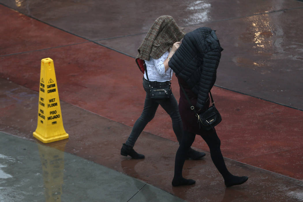 People walk in the rain at the Strip near Bally's casino-hotel in Las Vegas, Wednesday, Dec. 4, ...