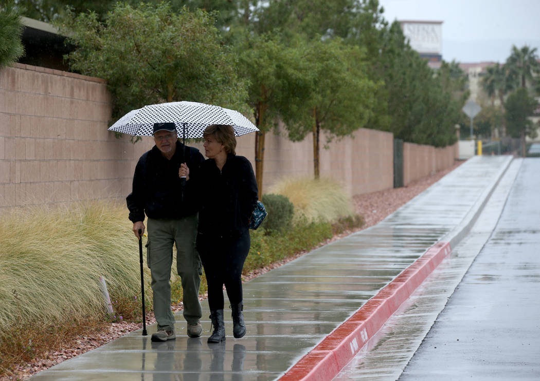 Ross and Angela Bracale share an umbrella under light rain near Russel Road and Boulder Highway ...