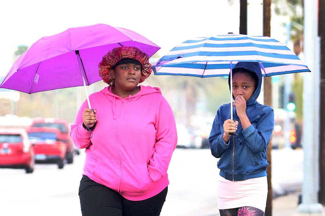 Pedestrians hold umbrellas to protect themselves from rain as they walk along Las Vegas Bouleva ...