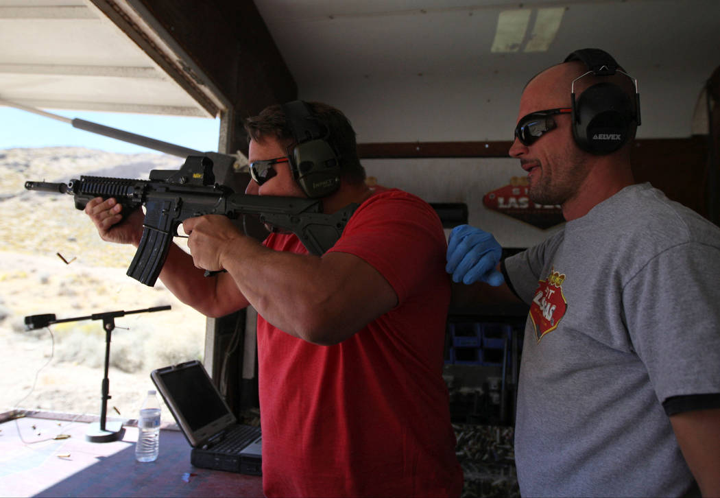 Carl Bunce, left, learns how to handle an automatic weapon from Shoot Las Vegas firearm instruc ...