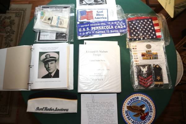 Items belonging to Lenoard Nielsen, a 93-year-old Pearl Harbor survivor, are displayed on a tab ...