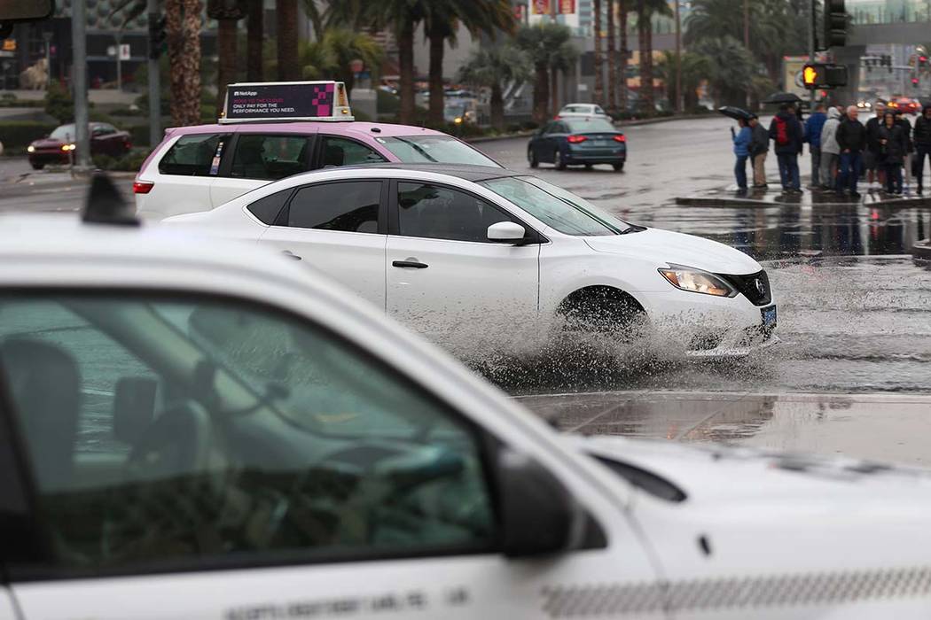 Drivers make their way to the Bellagio casino-hotel in Las Vegas on a flooded intersection as r ...