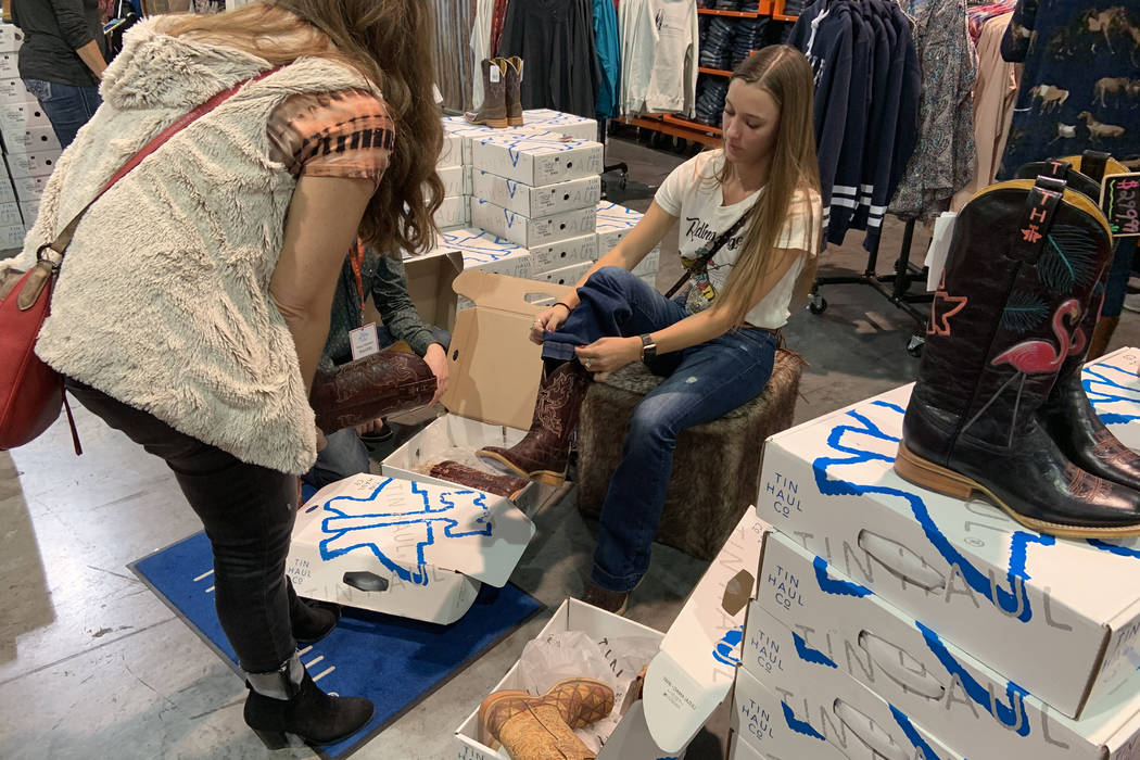 Caela Garland, right, of Nampa, Idaho, tries on a pair of cowboy boots as mom Rhonda Garland of ...