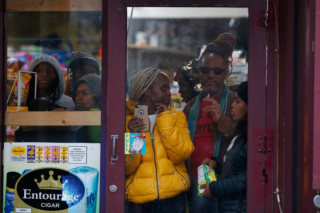 Bystanders look out from a store as law enforcement arrives at the scene following reports of g ...