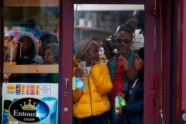 Bystanders look out from a store as law enforcement arrives at the scene following reports of g ...