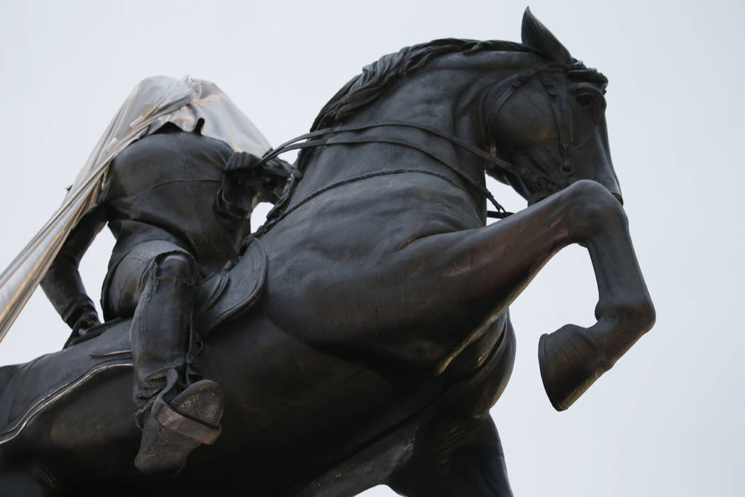 A tarp still covers part of a statue during the unveiling ceremony for a statue titled Rumor's ...