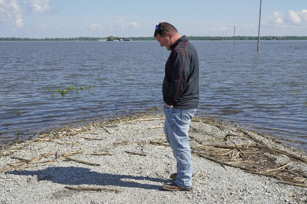 In this May 10, 2019 photo, Brett Adams stands where the road to his flooded farm disappears un ...