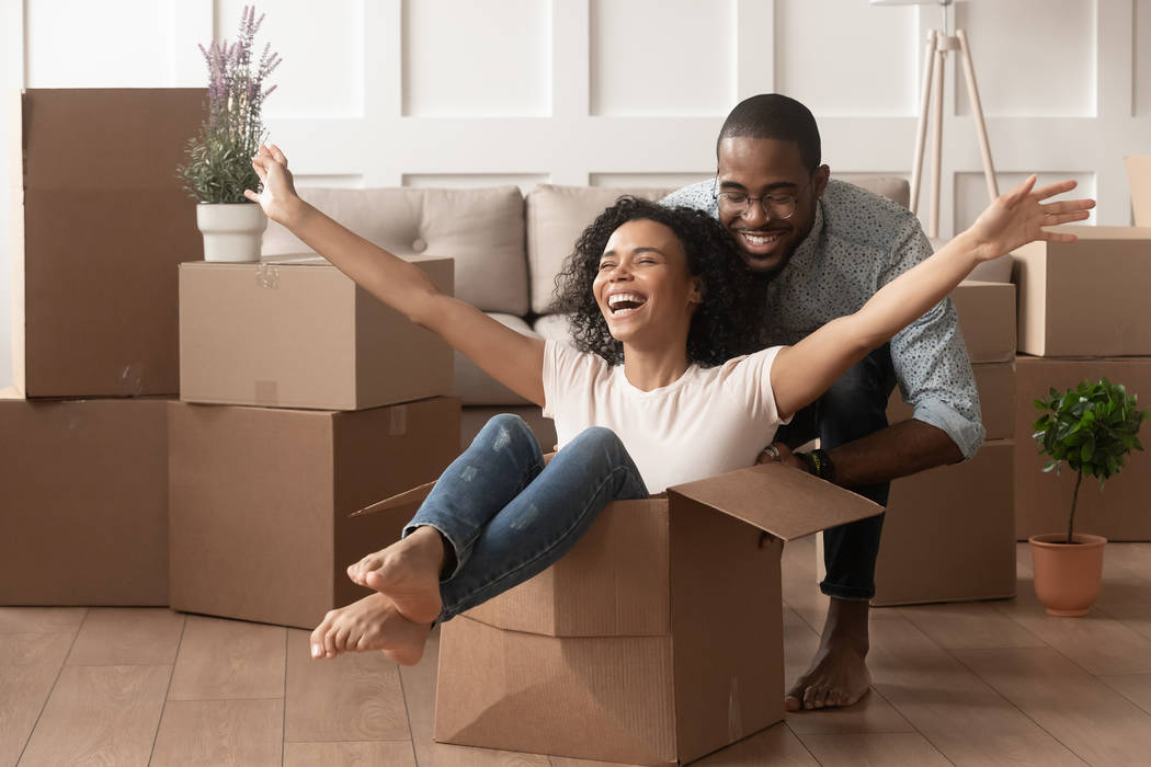 Happy african american young couple first time home buyers having fun unpacking laughing on mov ...