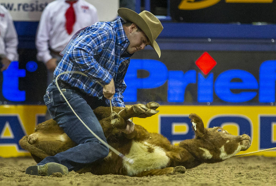 Tyler Milligan of Pawhuska, Okla., ties a calf while on a first place time of 7.50 seconds in T ...