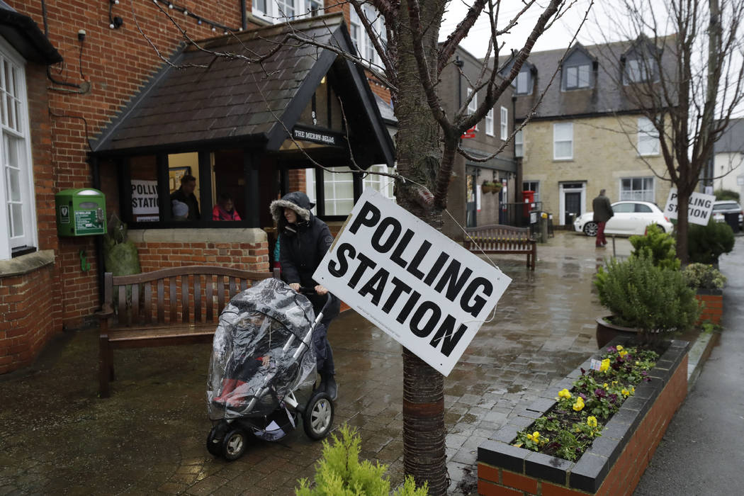 A sign hangs from a tree as rain falls outside a polling station at Merry Bells Village Hall in ...