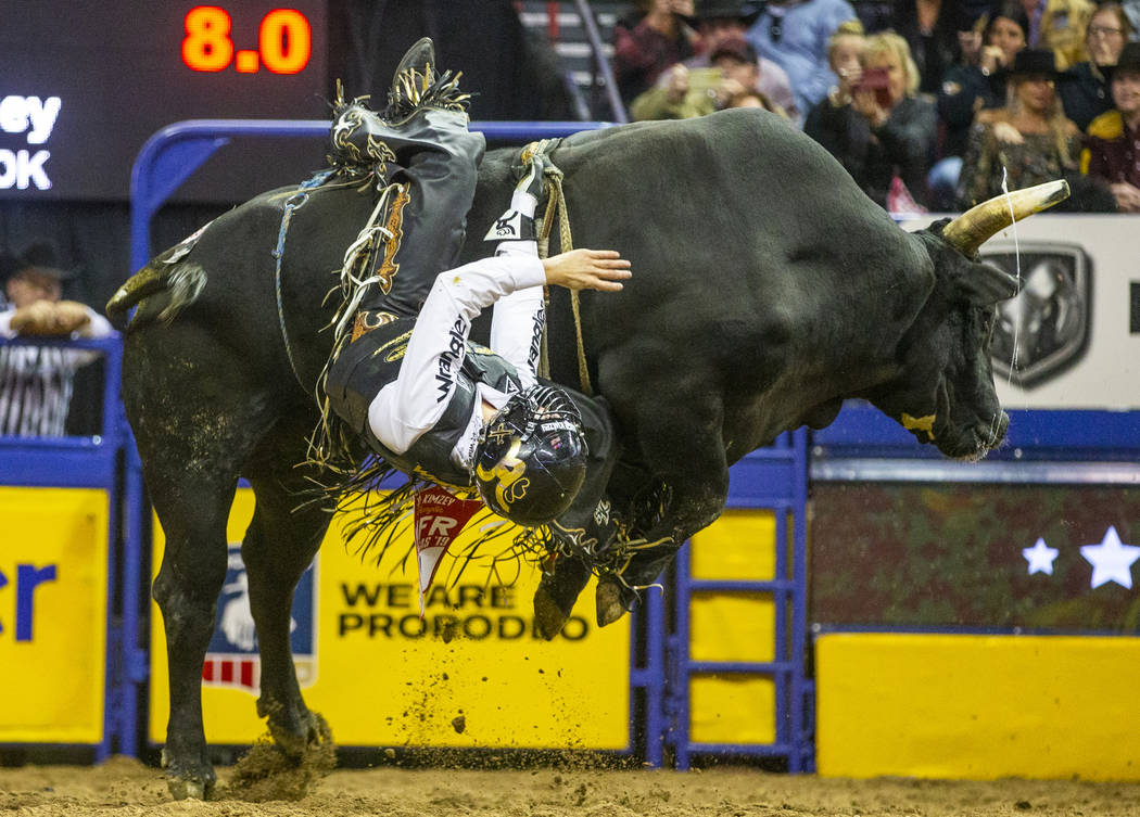 Sage Kimzey of Strong City, Okla, hangs on as he rides River Monster in Bull Riding during the ...