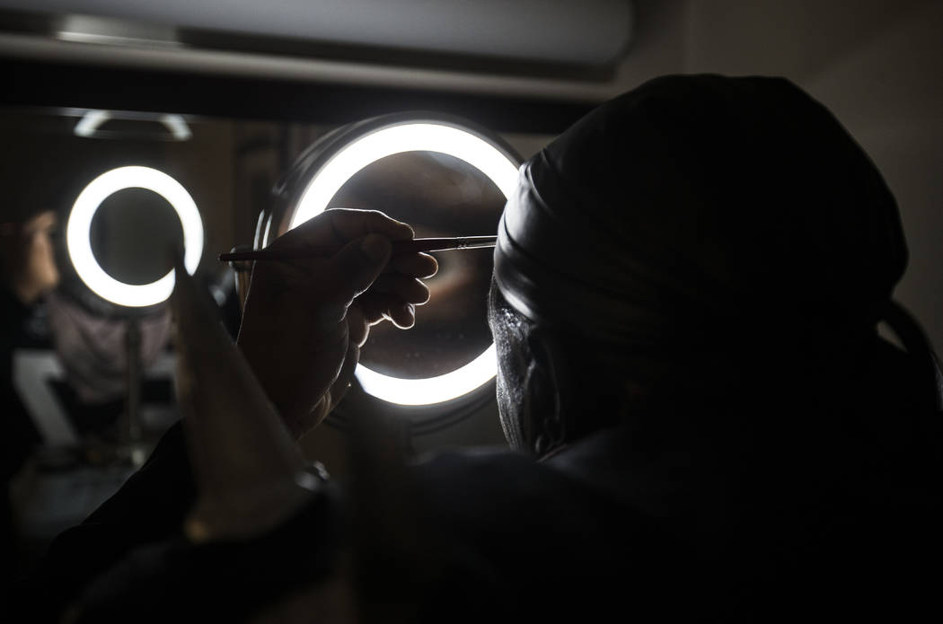 Raiders super fan Wayne Mabry, known as "Violator," applies makeup in his hotel room ...