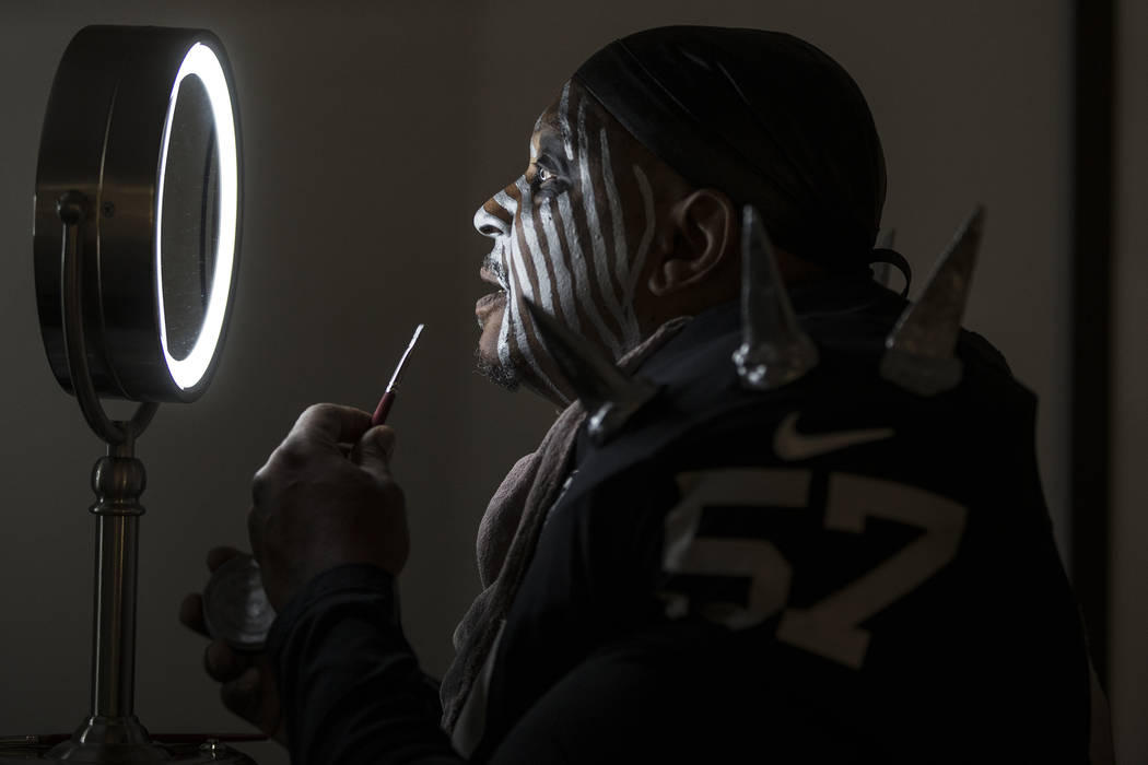 Raiders super fan Wayne Mabry, known as "Violator," applies makeup in his hotel room ...