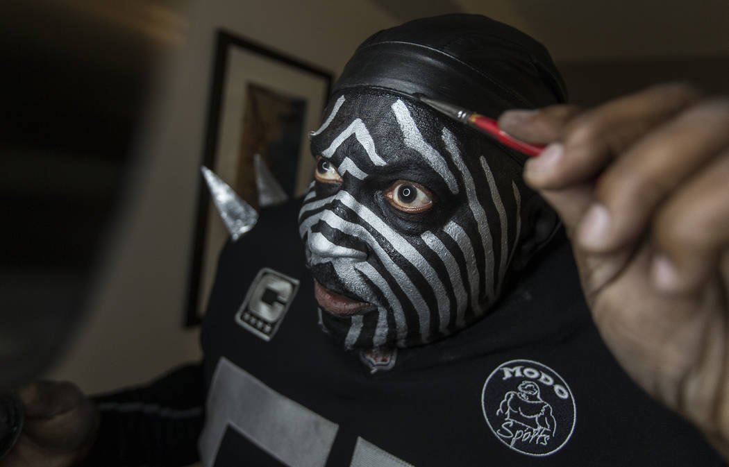 Raiders super fan Wayne Mabry, known as "Violator," applies makeup in his hotel room ...