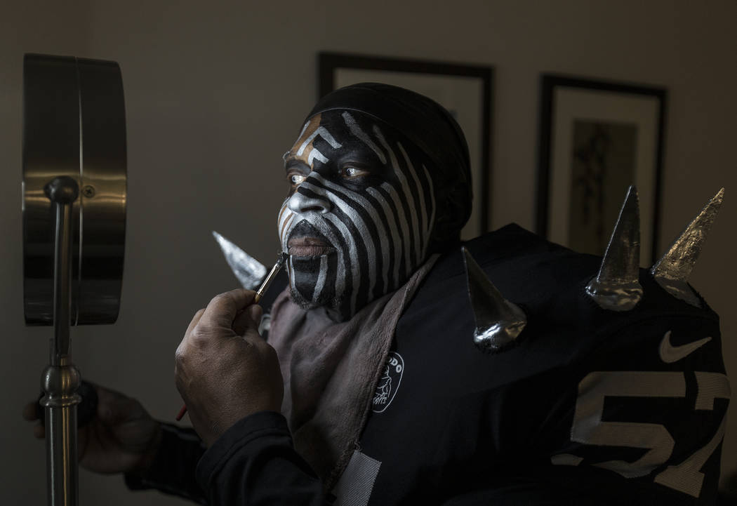 Raiders super fan Wayne Mabry, known as "Violator," applies makeup in his hotel room ...