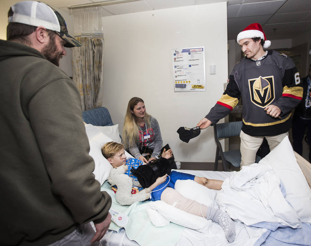 Golden Knights player Mark Stone hands a signed hat to Xavier Lee, 9, next to his mother Jodie ...