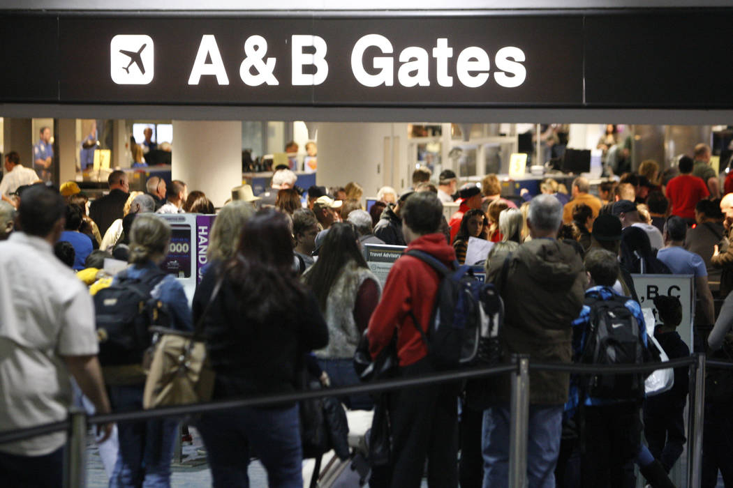 Passengers wait in line to go through security at McCarran International Airport Terminal 1 in ...