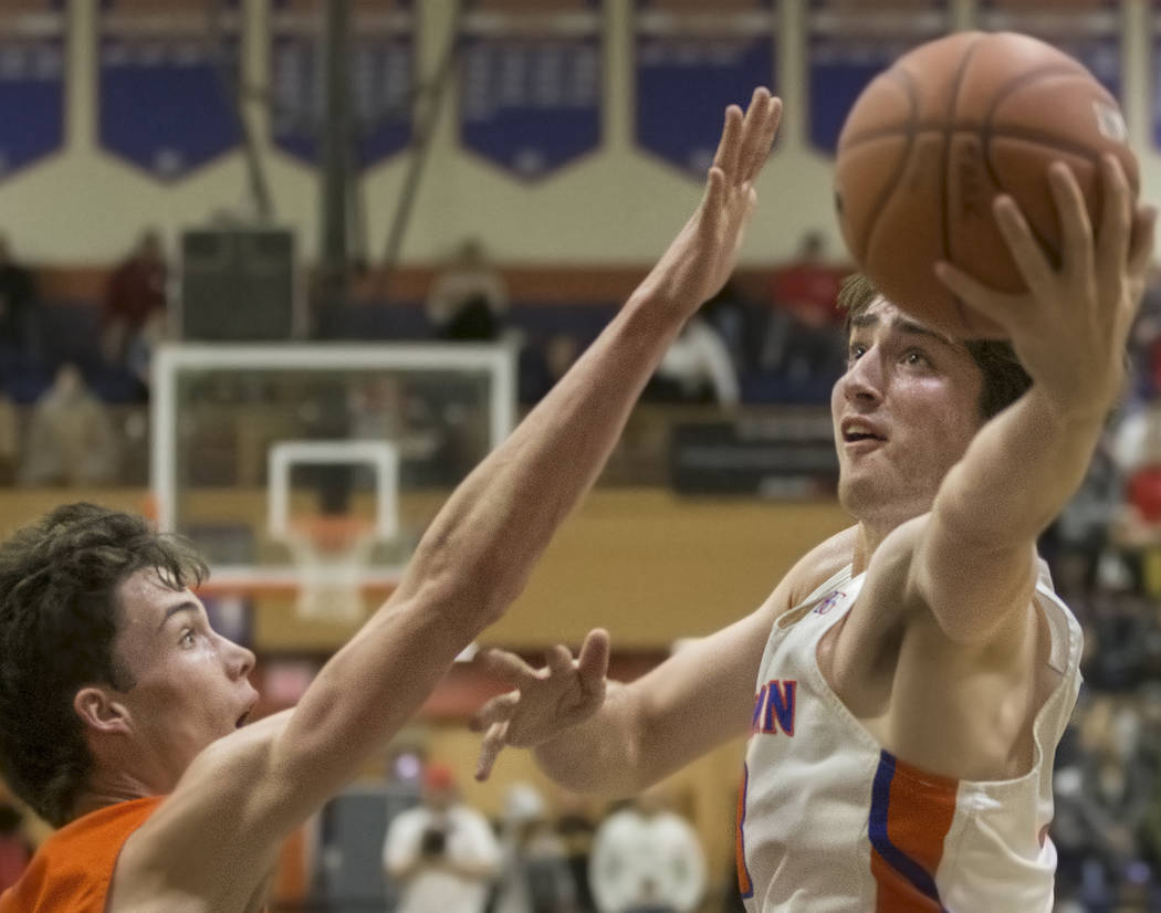 Bishop Gorman senior Braden Lamar (13) drives over Skyridge senior forward Luke Brower (21) in ...