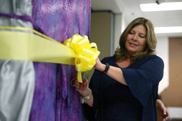 Principal Cathleen Furtado cuts a ribbon during an unveiling ceremony for a book bending machin ...