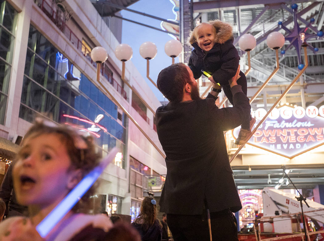 Rabbi Motti Harlig holds his son Mendel Harlig, 2, at a menorah lighting hosted by Chabad of So ...