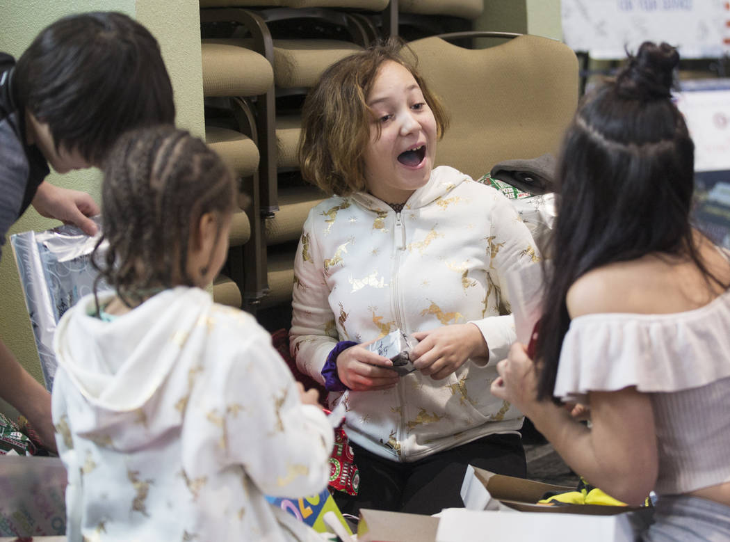 Brianna Aikens, 11, opens gifts with other survivors of the Alpine motel fire at SHARE Village ...