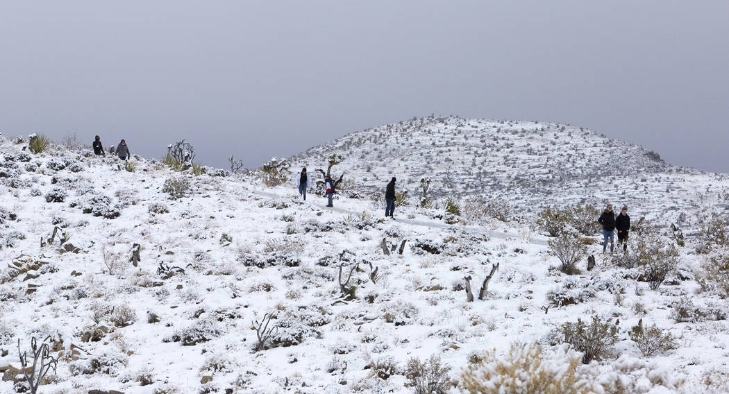People walk to a viewpoint at Red Rock Canyon Overlook in the snow on Thursday, Dec. 26, 2019, ...