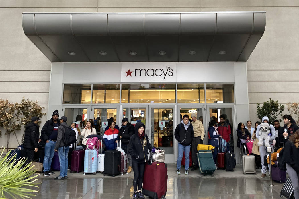 People shelter from the rain at the door to Macy's at Fashion Show mall in Las Vegas as they wa ...