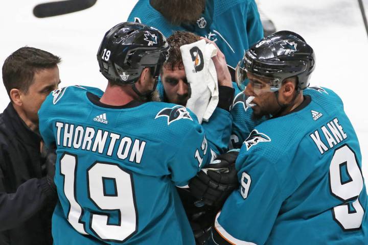 Sharks center Joe Pavelski, middle, is helped off the ice by Sharks left wing Evander Kane (9) ...