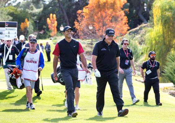 Tiger Woods, left, and Phil Mickelson walk to the fairway after teeing off from the first durin ...