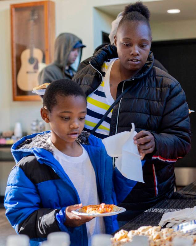 Andru Roach, 7, and Dayshena Thomas receive a meal during a luncheon for the tenants of the Alp ...