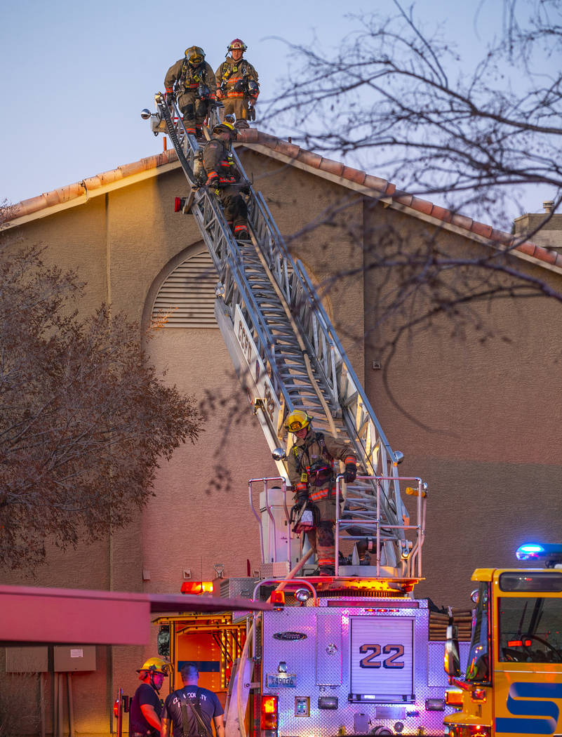 Firefighters with the Clark County Fire Department descend the roof of an apartment at the Glor ...