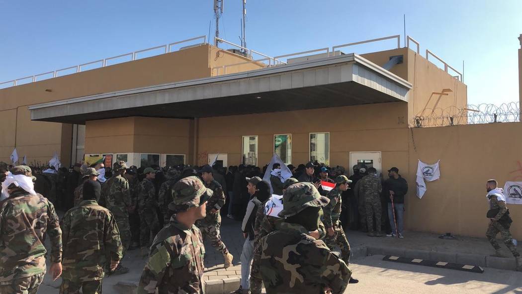 Dozens of Iraqi Shiite militia supporters are seen outside the U.S. embassy compound in Baghdad ...