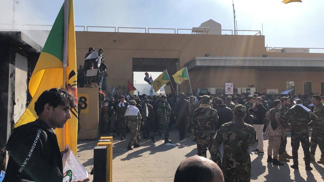 Dozens of Iraqi Shiite militia supporters are seen outside the U.S. embassy compound in Baghdad ...