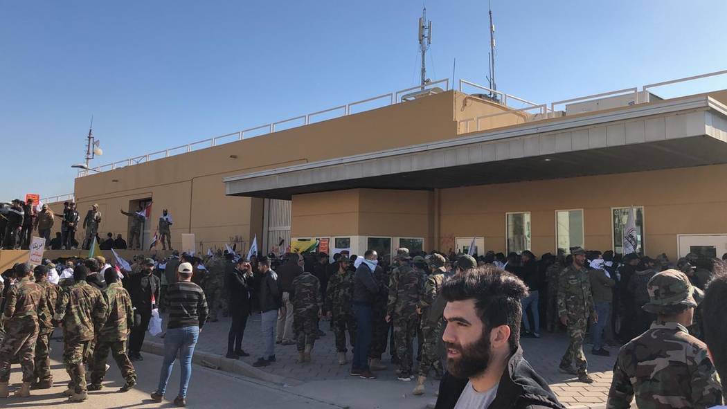 Dozens of Iraqi Shiite militia supporters are seen outside the U.S. embassy compound in Baghdad ...