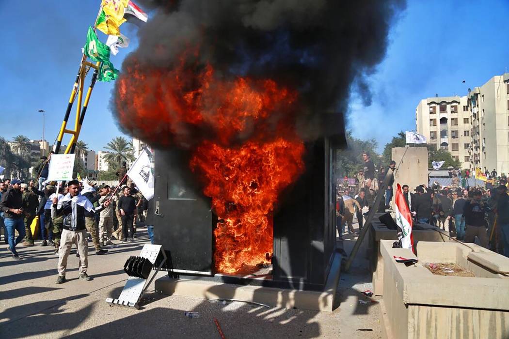 Protesters burn property in front of the U.S. embassy compound, in Baghdad, Iraq, Tuesday, Dec. ...