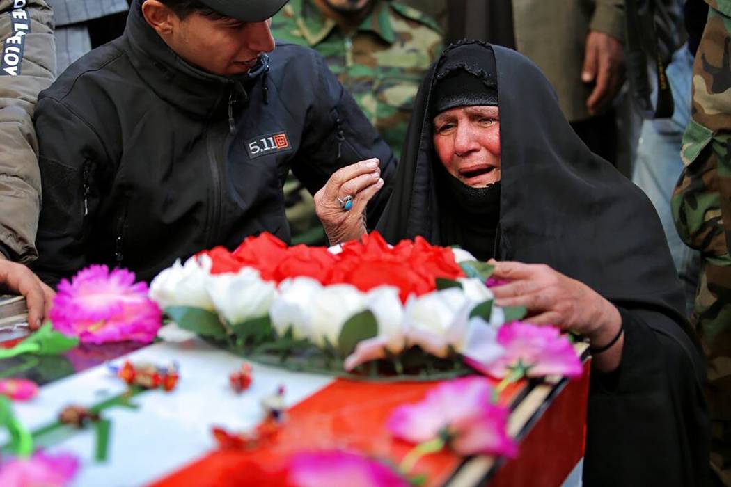 Mourners pray by coffins of Iran-backed Popular Mobilization fighters killed in a U.S. airstrik ...